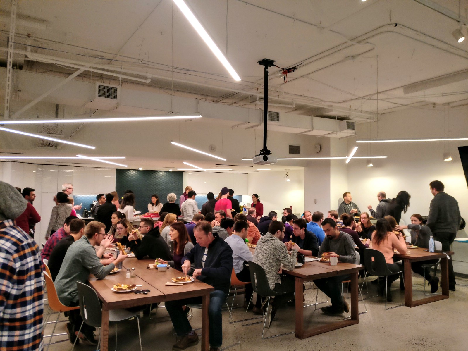 Celebrating some key milestones at Klipfolio with some cake and pizza! - People eating food in a large kitchen